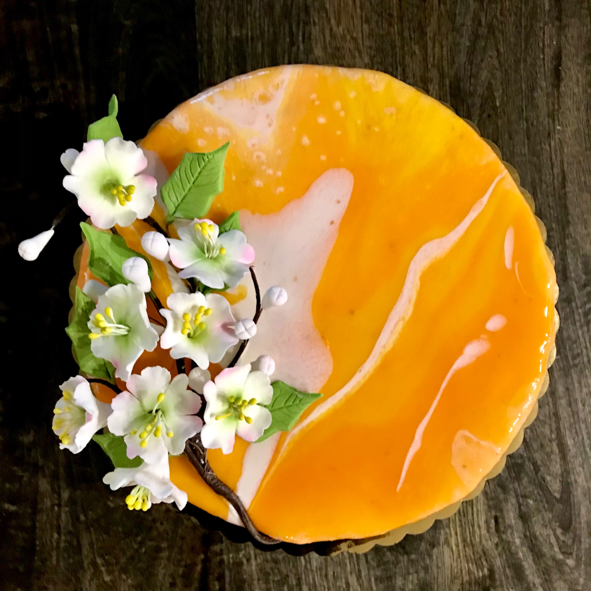 Orange glazed cake with hand-sculpted white blossoms