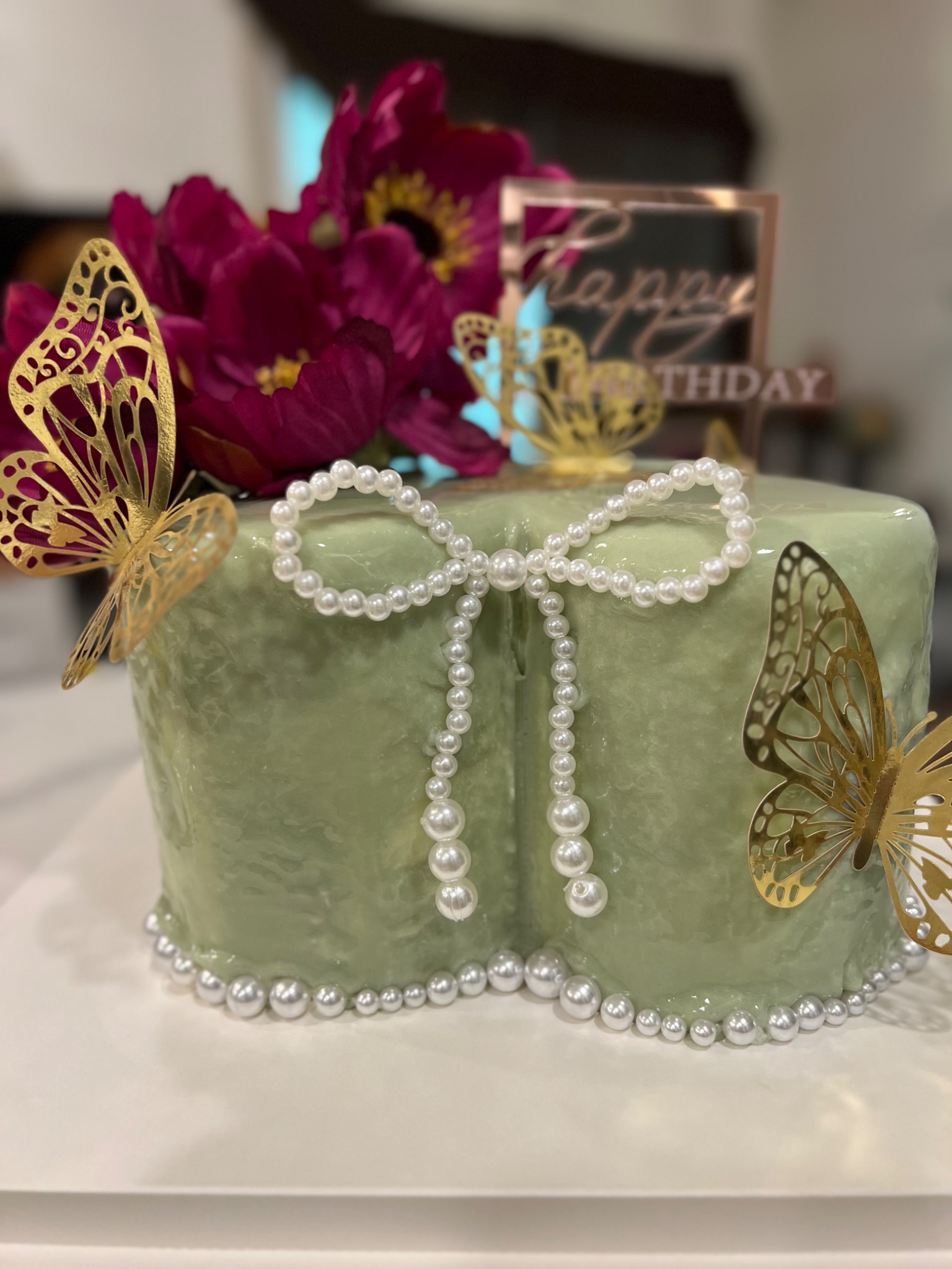 Soft green cake with pearl bow and gold butterflies